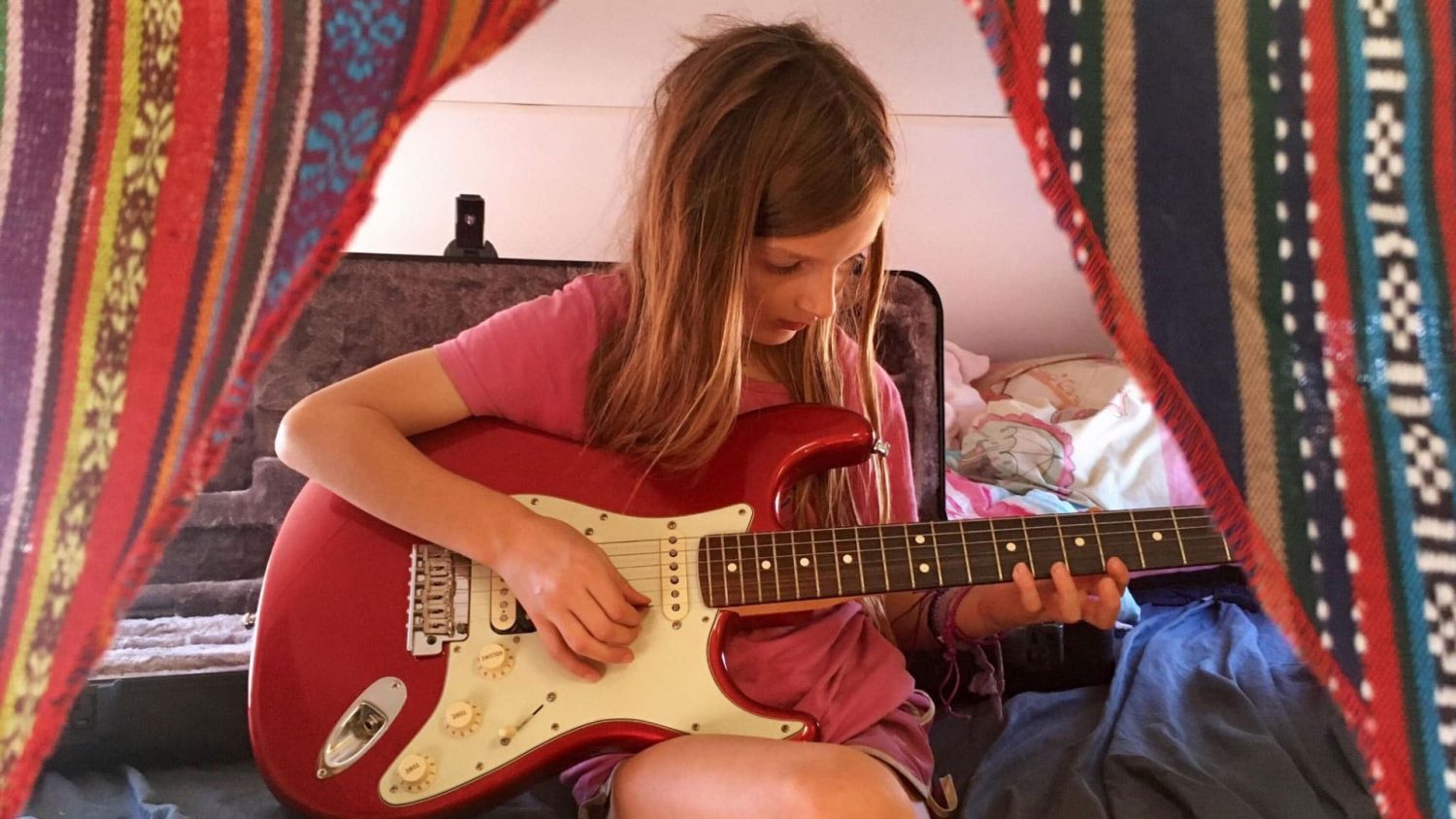 Young girl playing a guitar in a camper van