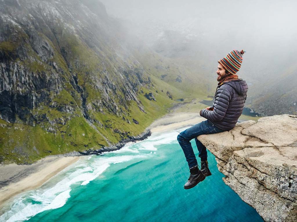 campervan man Mike Hudson from VanDog Traveller sat on the edge of a cliff in Norway